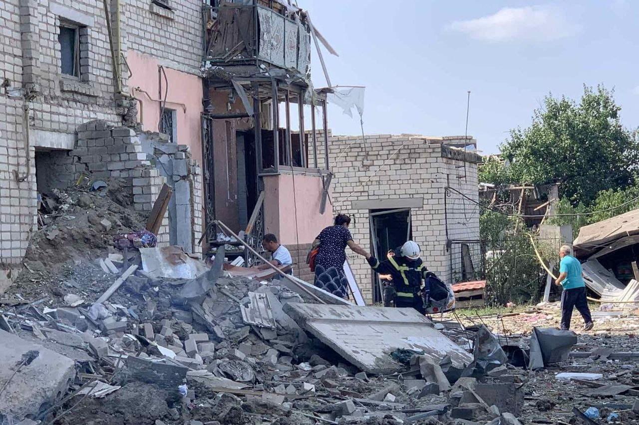 Rescuer helps a woman to be evacuated from a residential building damaged by a Russian missile strike in Voznesensk