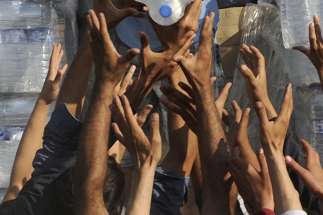 Refugees and migrants are handed out bottles of water as they wait to cross the borders of Greece with Macedonia, near the village of Idomeni September 4, 2015. European Union officials are preparing to push EU governments to take in many more asylum-seek