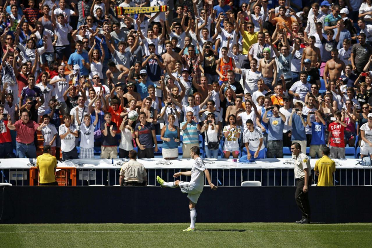 'Gareth Bale of Wales kicks a ball to fans at the Santiago Bernabeu stadium in Madrid, September 2, 2013. Thousands of Real Madrid fans flocked to the Bernabeu to welcome Gareth Bale on Monday after t