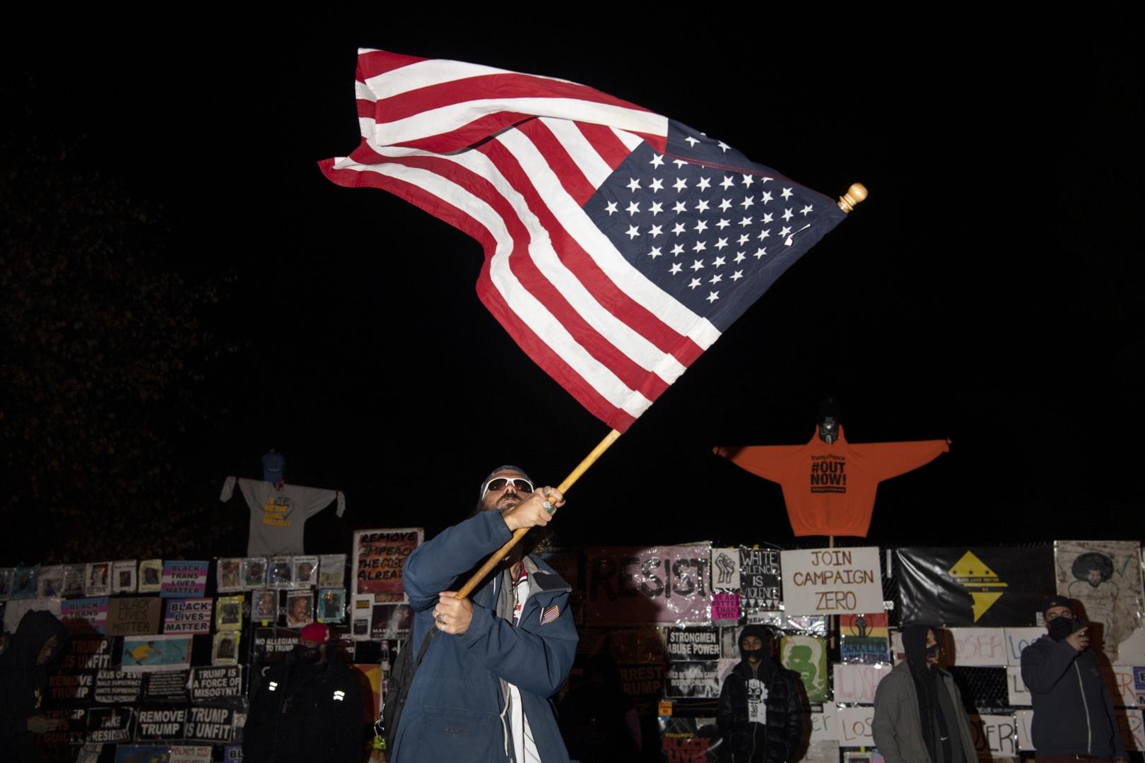 UNITED STATES - NOVEMBER 3: A man waves an American flag as people gather at Black Lives Matter Plaza during the 2020 Presidential election in Washington on Tuesday, Nov. 3, 2020. (Photo by Caroline Brehman/CQ Roll Call) Photo via Newscom Newscom/PIXSELL