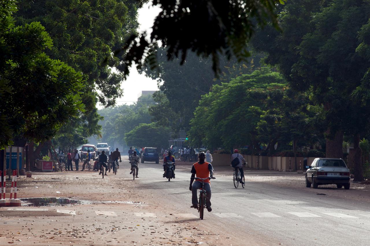 FILE PHOTO: People ride bicycles and motorcycles on a street in Ouagadougou