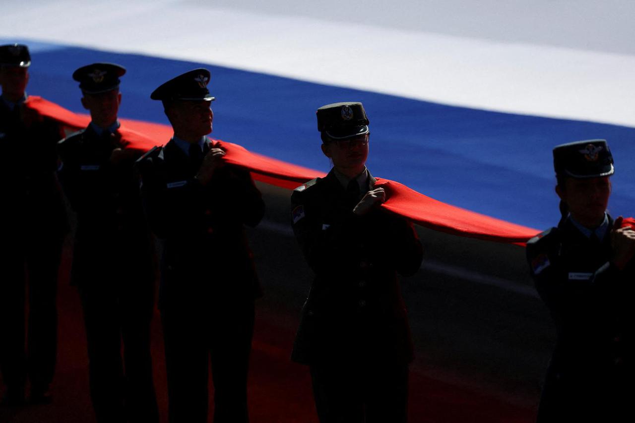 Serbian soldiers carry a large Serbian flag-themed flag during a military parade in Belgrade