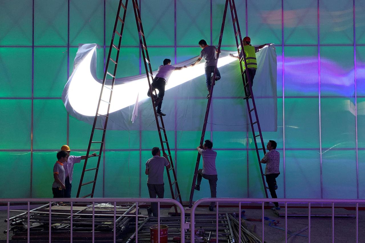 FILE PHOTO: Workers install a Nike logo lamp outside the Wukesong Arena in Beijing