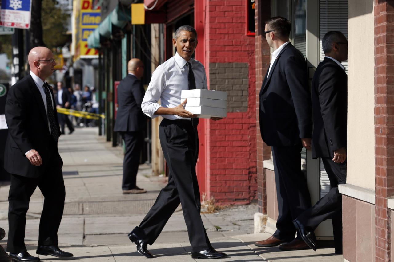 U.S. President Barack Obama carries boxes of pastries into a Pat Quinn campaign office in Chicago, Illinois October 20, 2014. Quinn is running for re-election as Governor of Illinois.  REUTERS/Kevin Lamarque (UNITED STATES - Tags: POLITICS ELECTIONS)