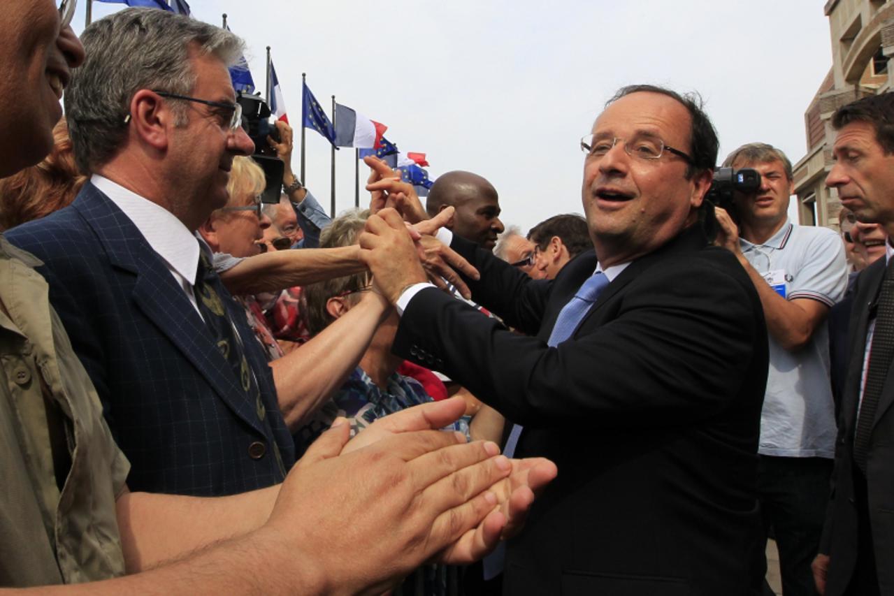 'French President Francois Hollande (R) shakes hands with residents as he arrives for a meeting focus on employment at the Urban Community of Dunkirk, northern France, July 23, 2103.  REUTERS/Pascal R
