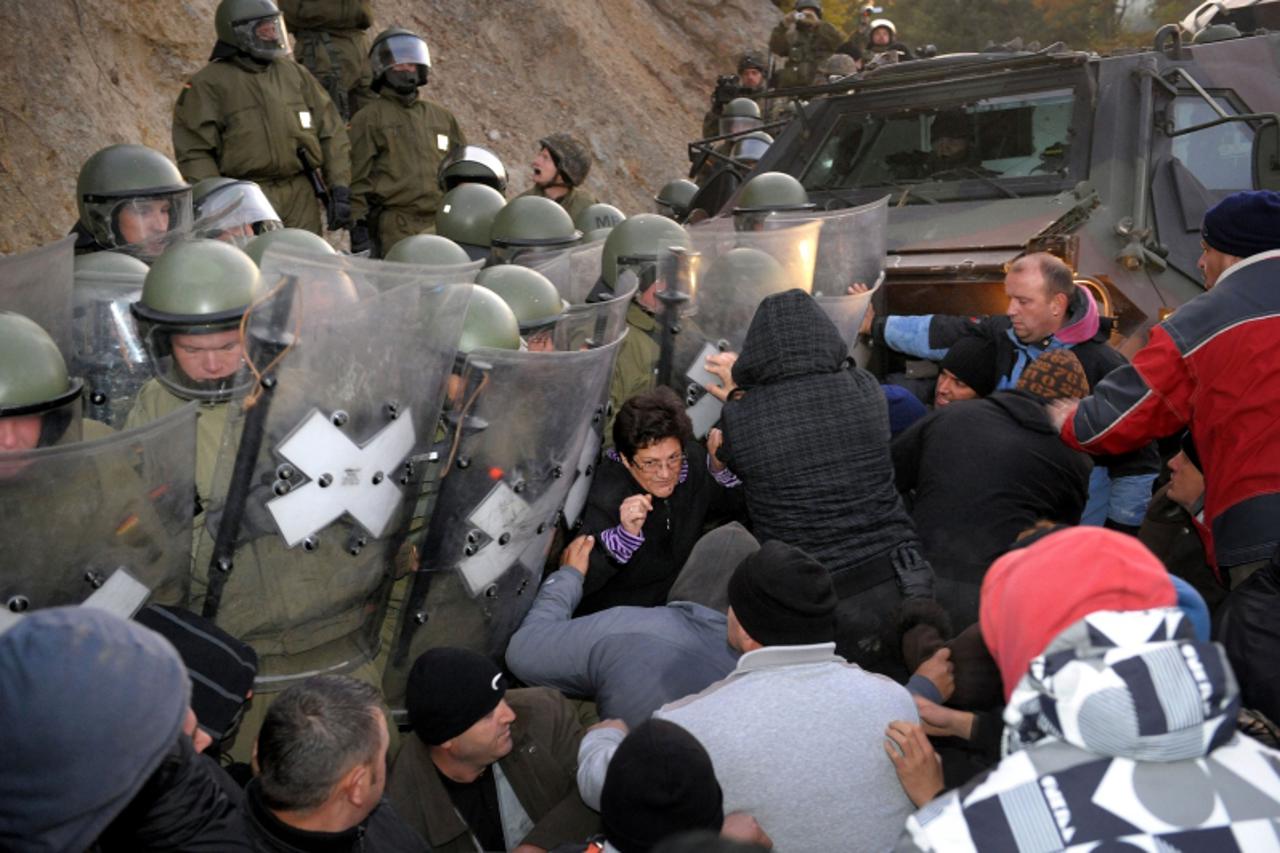 'German and Austrian troops push Kosovo Serbs to dismantle the roadblock near the village of Jagnjenica on October 20, 2011. NATO-led peacekeeping troops fire tear gas to disperse protesters as they b