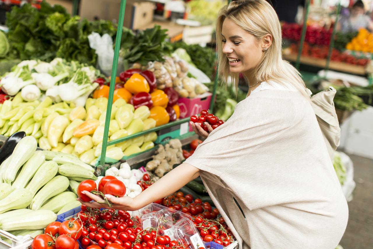 Young woman buying vegetables at the market