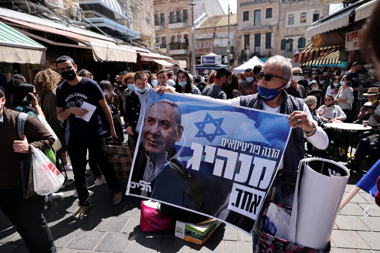 A supporter holds up a Likud party election campaign poster depicting it's leader, Israeli Prime Minister Benjamin Netanyahu, ahead of the March 23 general election, in Jerusalem