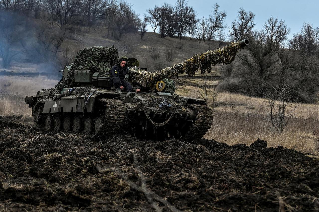Ukrainian servicemen ride atop of a tank at a position near a frontline in Zaporizhzhia region