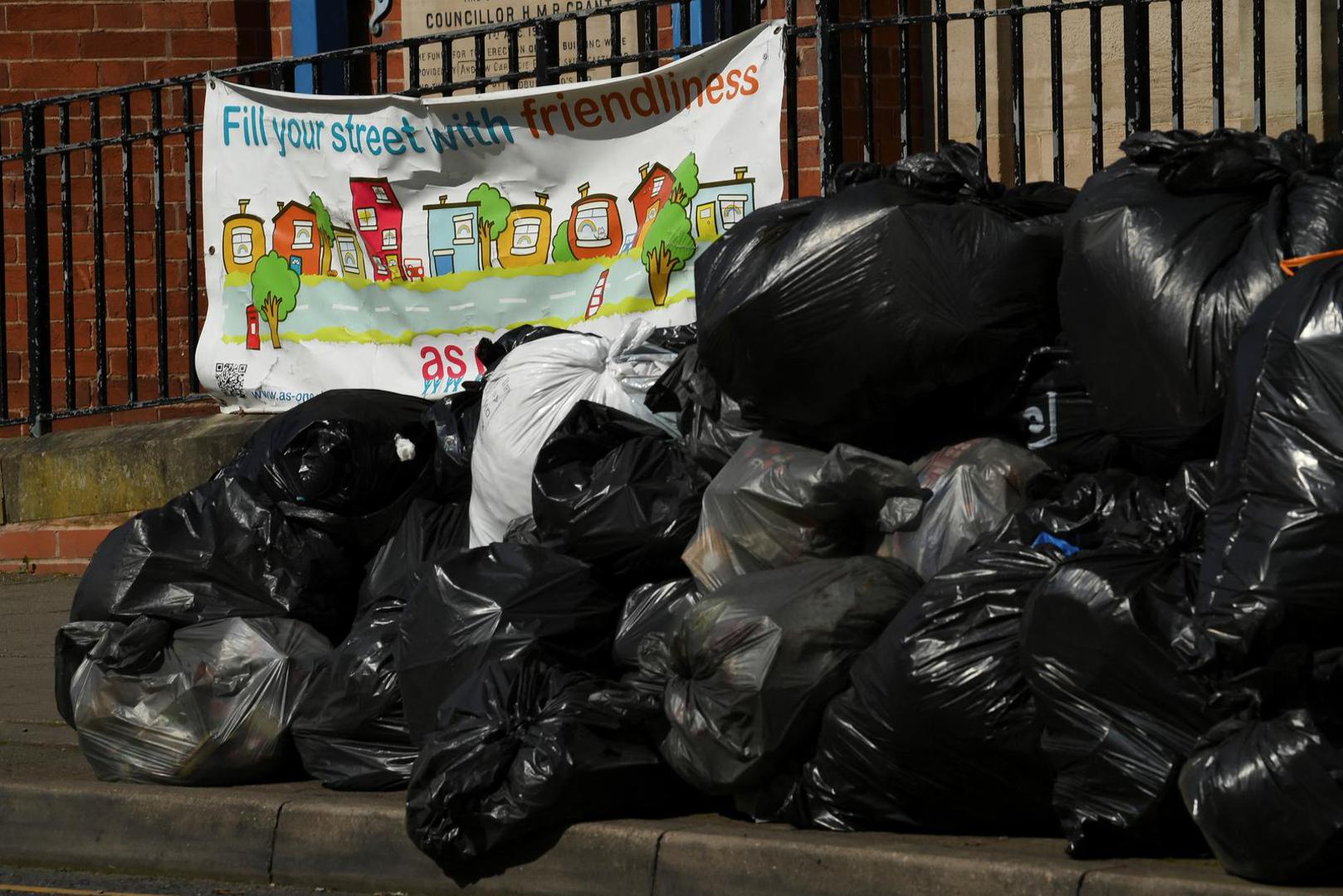 A sign reading "Fill your street with friendliness" is seen next to a large pile of rubbish on the pavement, as the strike action by Birmingham bin workers represented by the Unite union enters its fourth week, in Stirchley, Birmingham, Britain, April 2, 2025. REUTERS/Jaimi Photo: JAIMI JOY/REUTERS