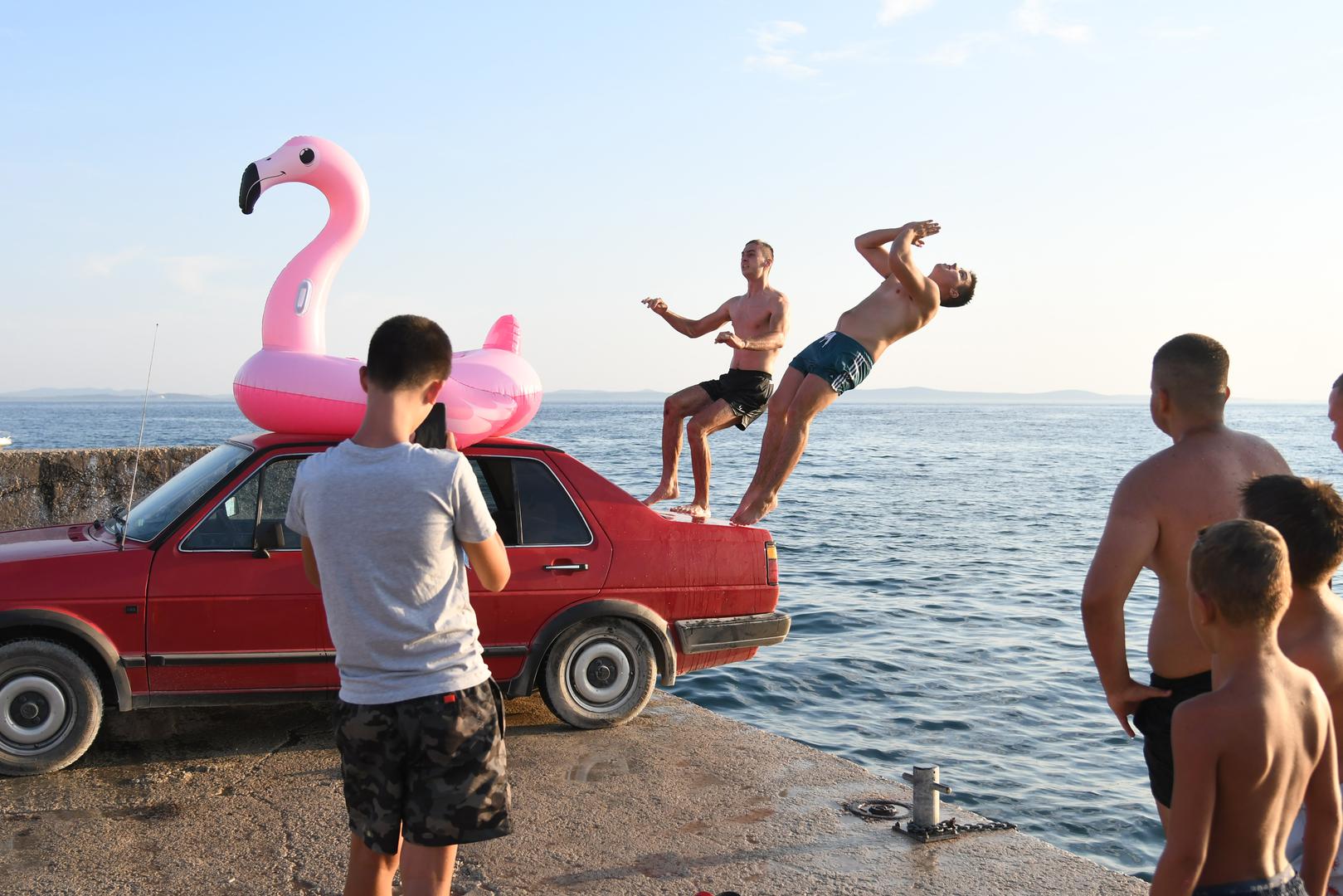 Umjesto klasičnog mola, iskoristili su ono što su imali – crveni automobil parkiran tik uz obalu. 