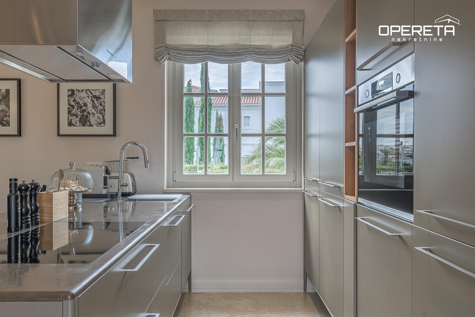 U prizemlju se nalaze ulazni hodnik, veliki dnevni boravak s kuhinjom i blagovaonicom, jedna spavaća soba s kupaonicom te izlaz na vrt i sunčalište s bazenom 8x4 metra. 