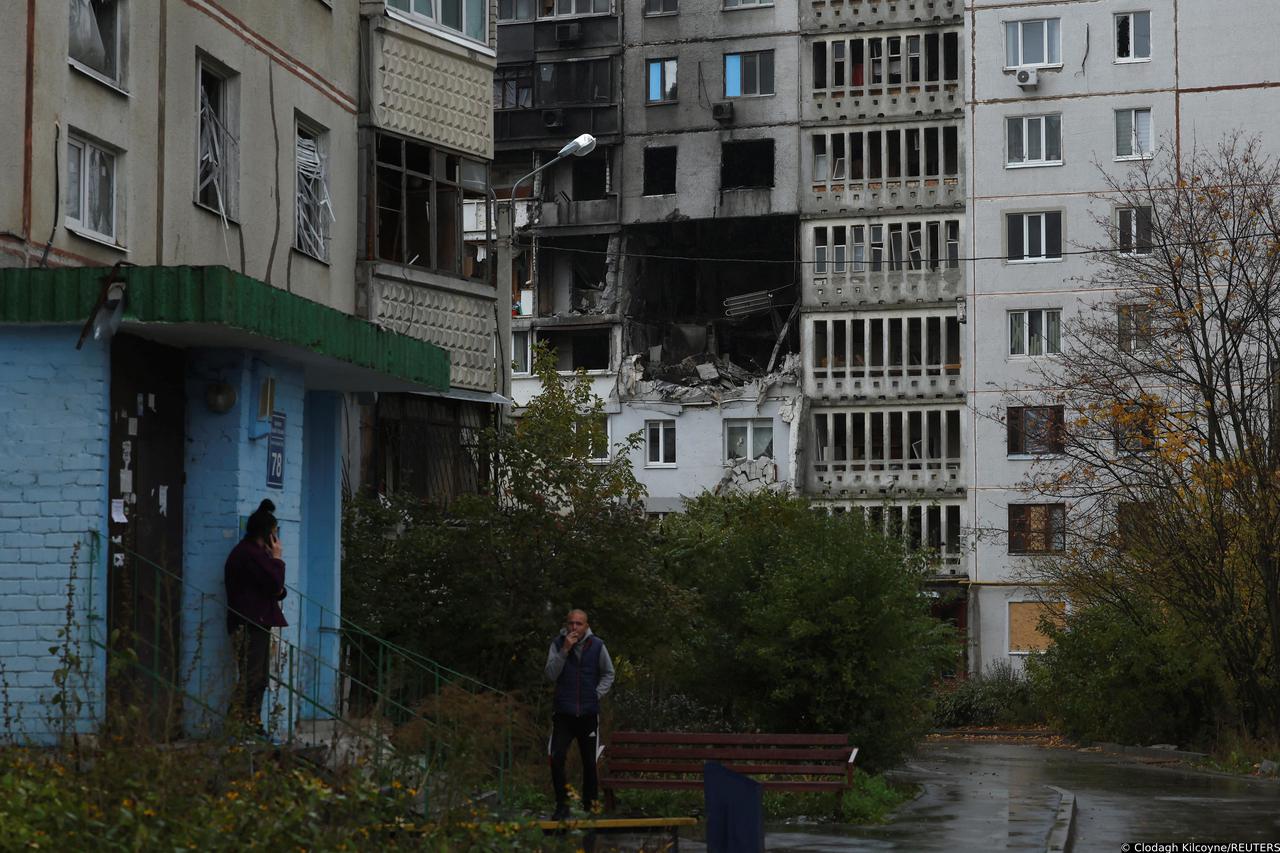 A couple wait for police to arrive to report stolen posessions from their heavily damaged apartment, in Kharkiv
