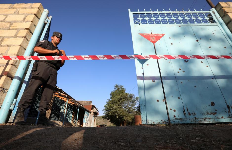 A law enforcement officer guards next to a house damaged during a recent shelling by Armenia's forces, in armed clashes on the border between Azerbaijan and Armenia in the village of Agdam, Azerbaijan