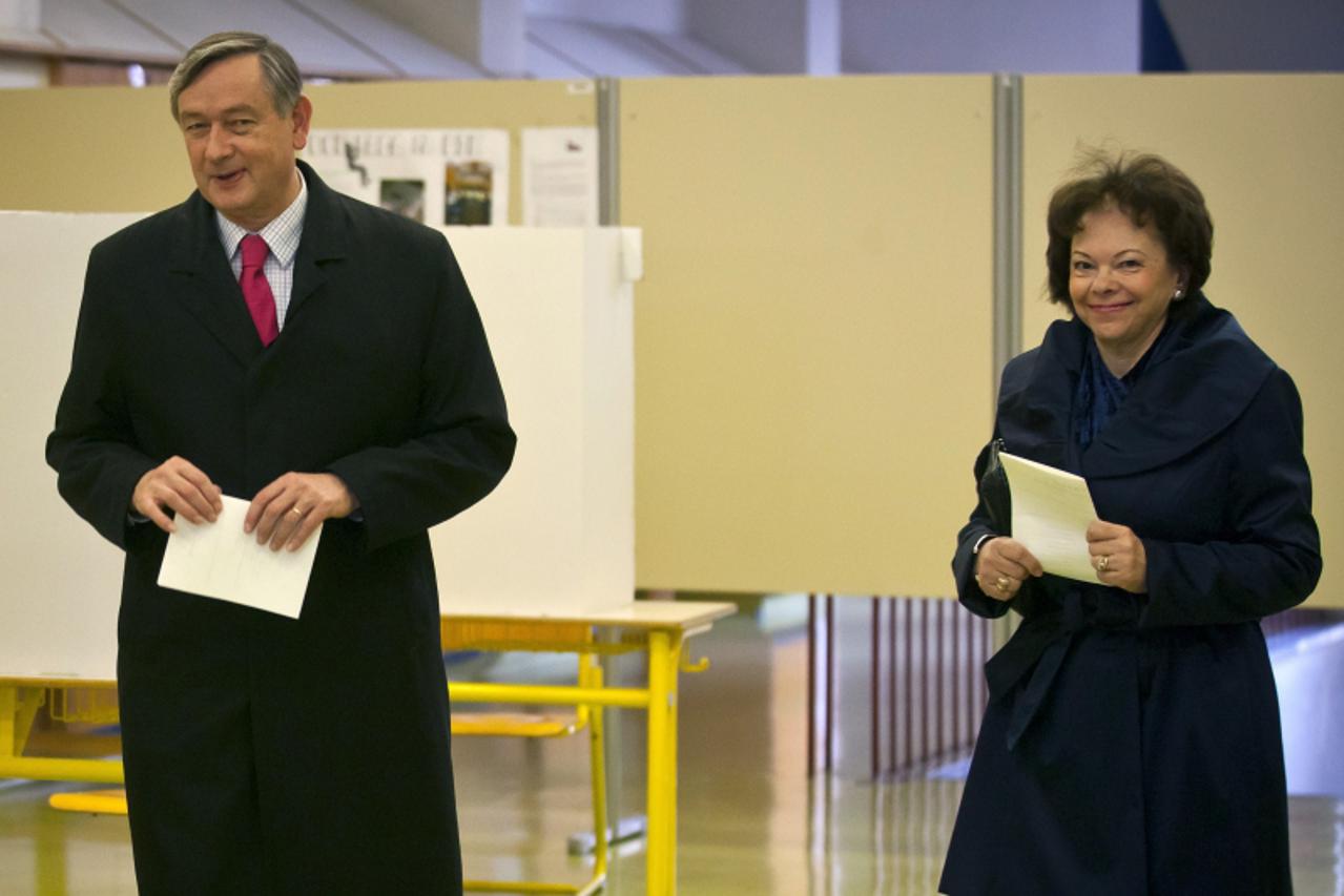 \'Slovenian President Danilo Turk (L) and his wife Miklic walk with their ballots before voting at a polling station in Ljubljana on December 4, 2011 during early parliament elections. Slovenia\'s cen