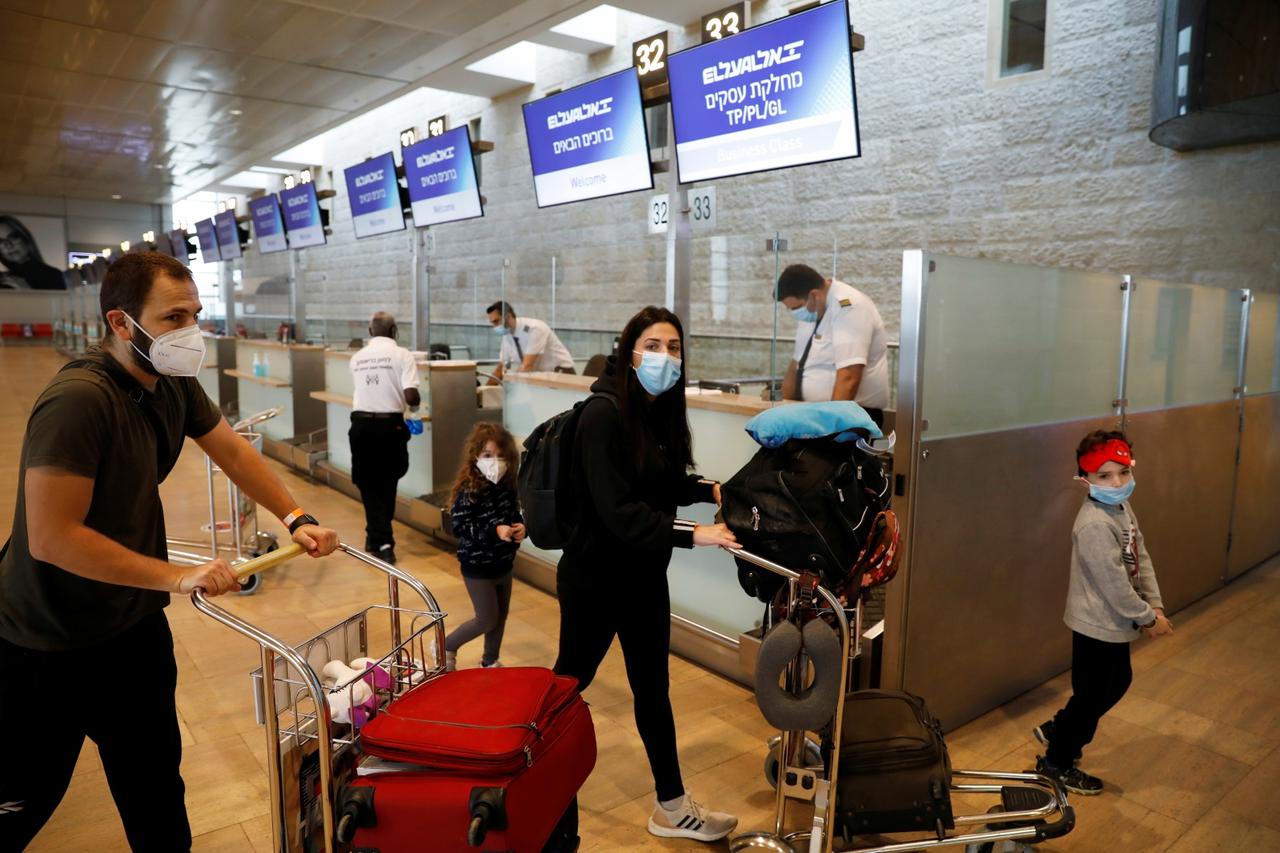 Passengers wearing masks push trolleys at the departures terminal at Ben Gurion International Airport, in Lod, near Tel Aviv, Israel