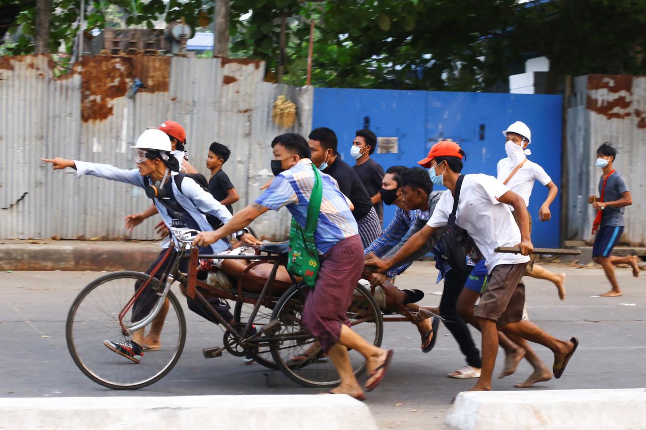 People transport a person who was shot during a security force crackdown on anti-coup protesters in Thingangyun, Yangon