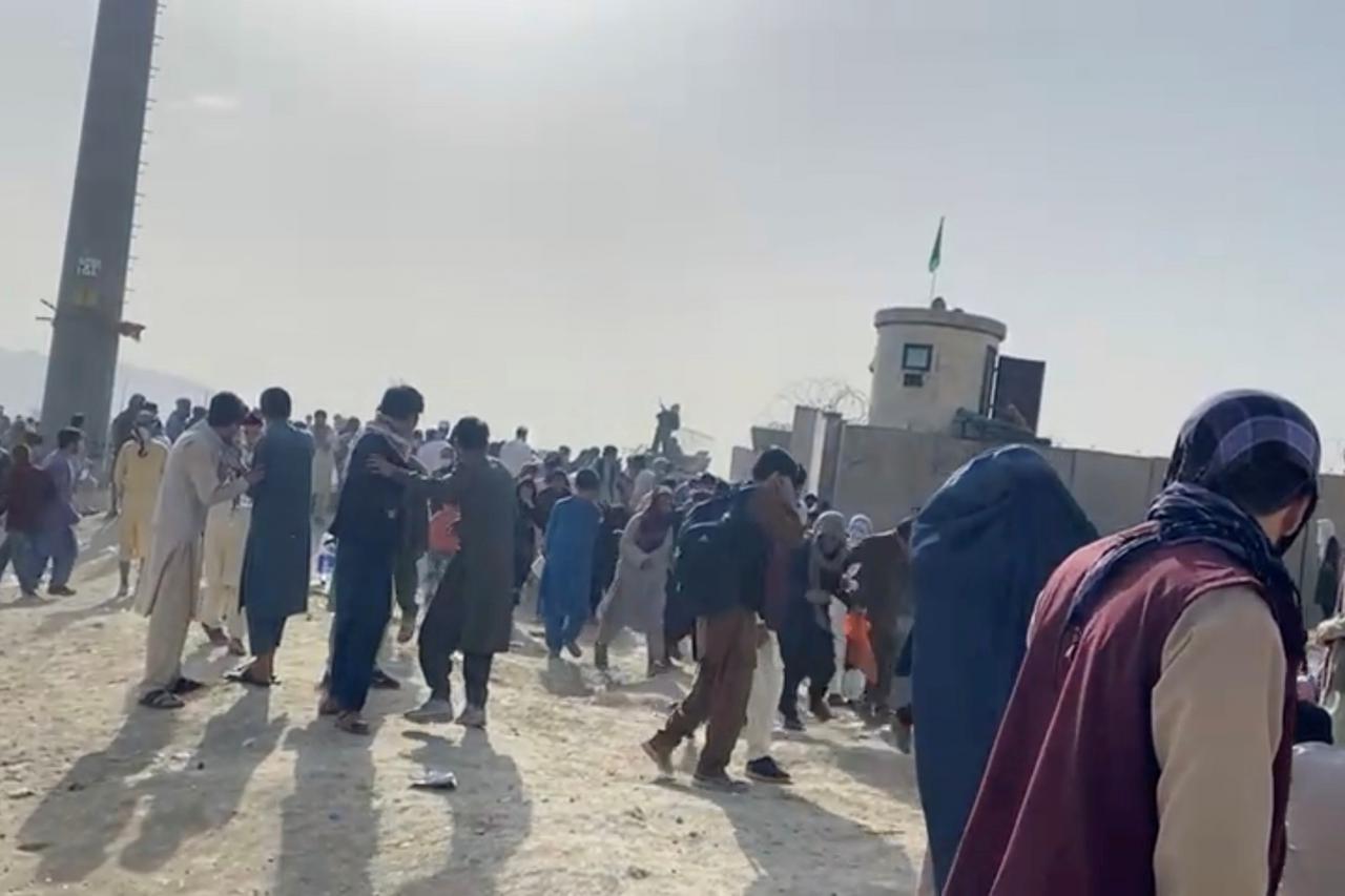 People gathered outside the airport react to gunfire, in Kabul