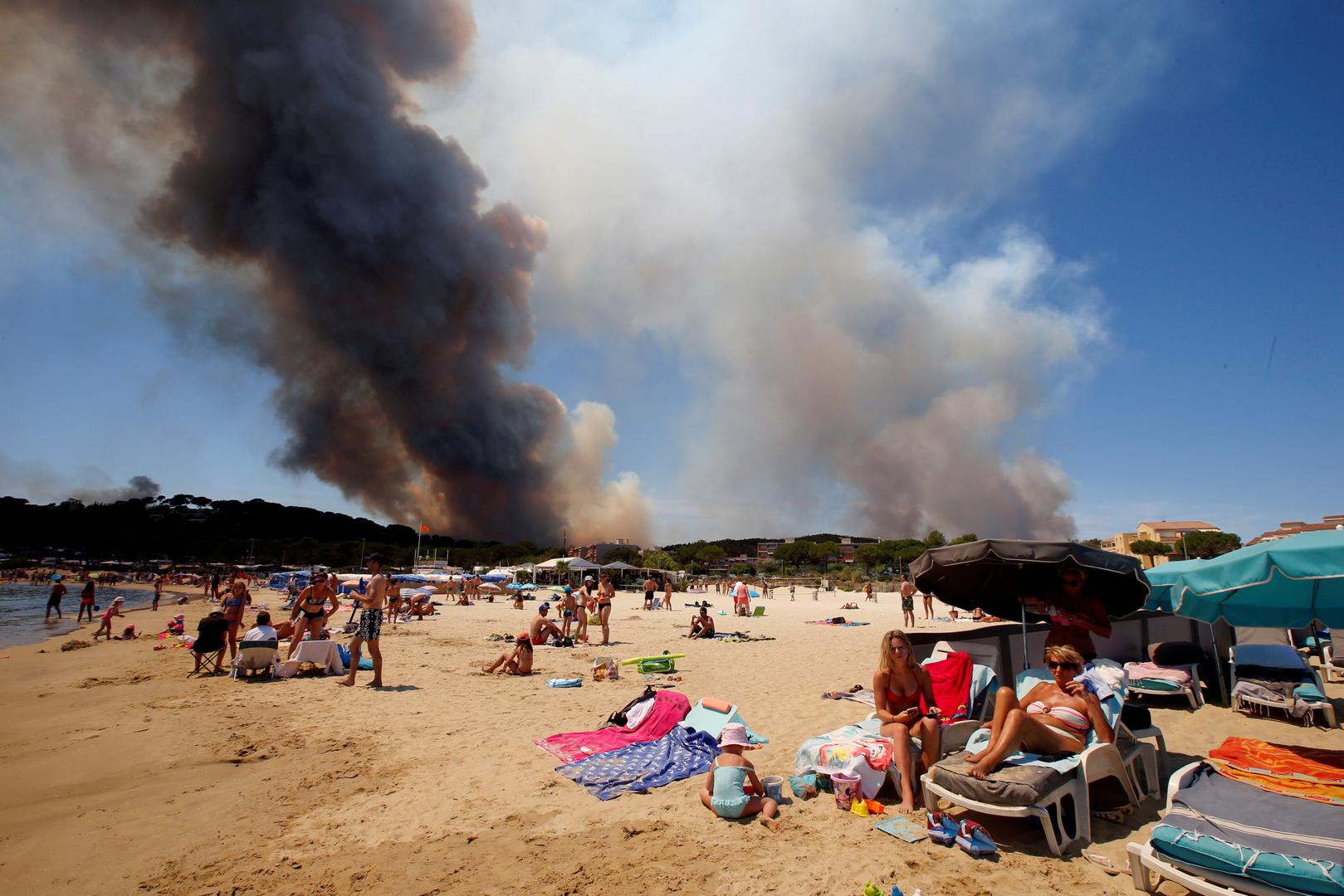 Dim se uzdiže prema nebu tijekom požara dok se turisti odmaraju na francuskoj plaži u Bormes-les-Mimosas.