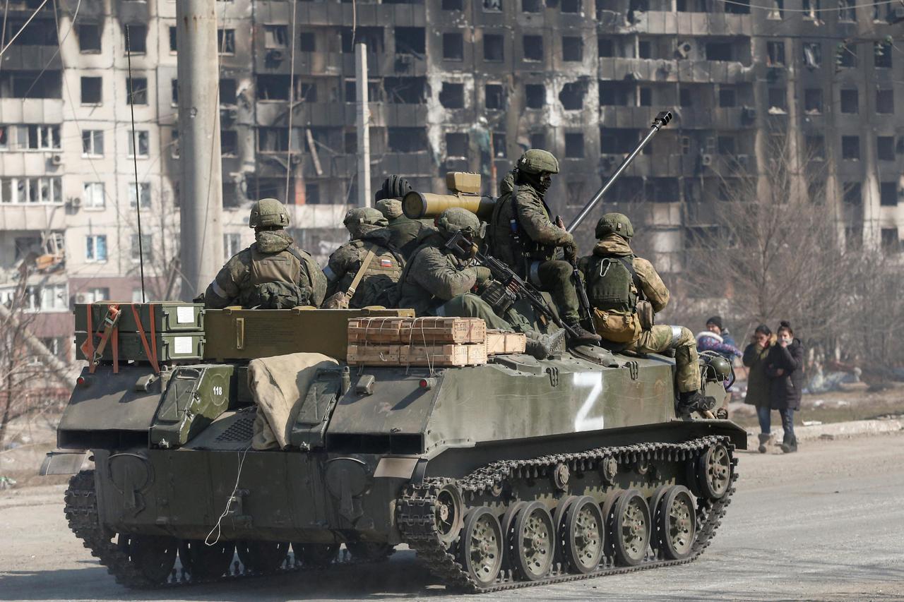 Service members of pro-Russian troops are seen atop of an armoured vehicle in the besieged city of Mariupol