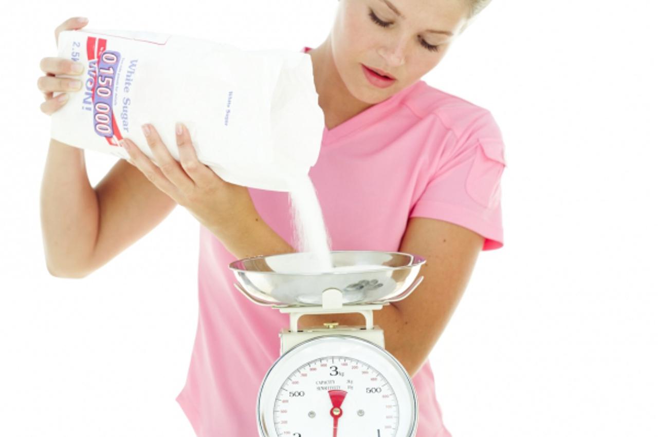 'woman pouring sugar onto a weighting machine'