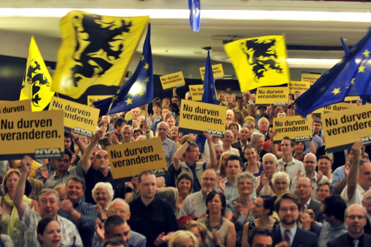 'people waving flemish flags as the chairman of the Flemish nationalist party N-VA, Bart De Wever (4G) surrounded with candidates sing the national Flemish anthem at the end of his seepch on June 6, 2