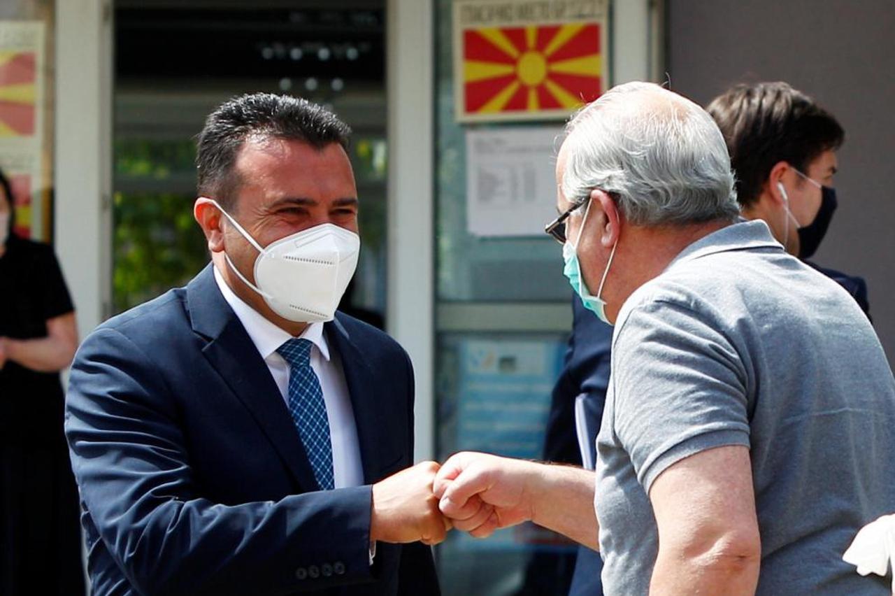 Macedonian Former Prime Minister and leader of the ruling SDSM party Zoran Zaev gives a fist bump to a voter as he leaves a polling station after voting during the general election, in Strumica