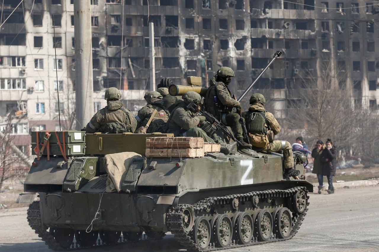 Service members of pro-Russian troops are seen atop of an armoured vehicle in the besieged city of Mariupol