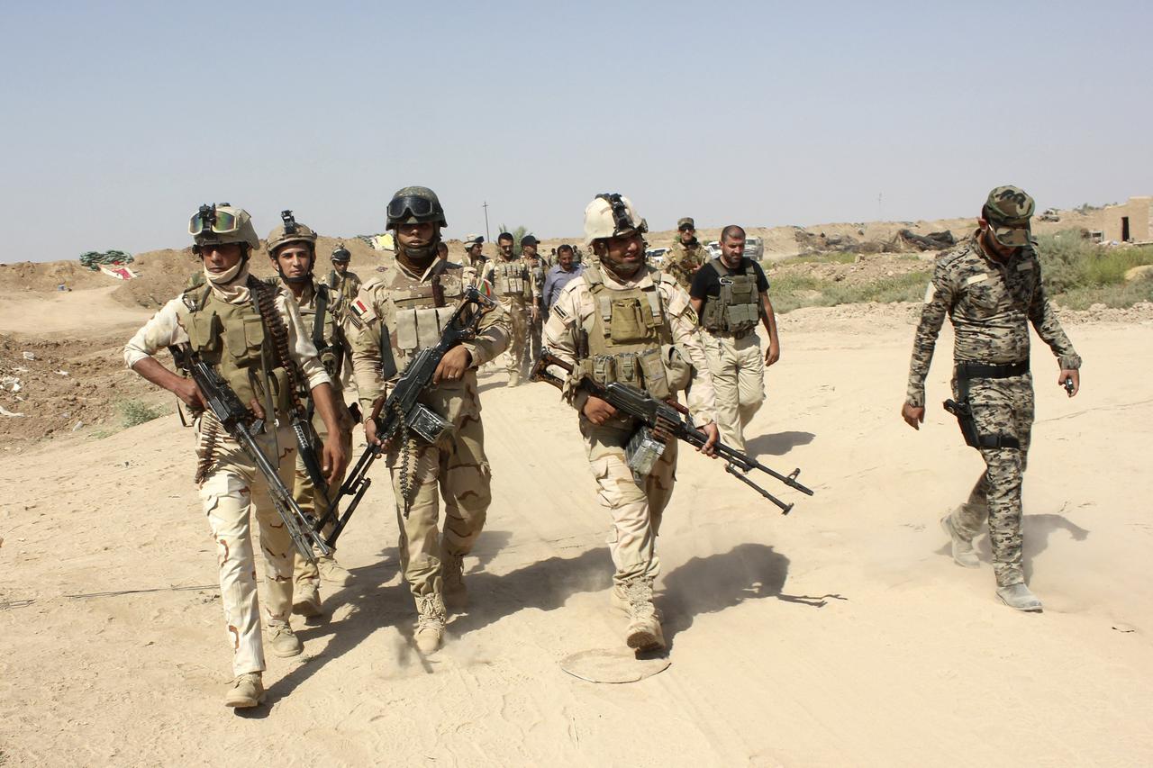 Iraqi security forces and Iraqi Shi'ite volunteers carry their weapons during an intensive security deployment to fight against militants of the Islamic State, formerly known as the Islamic State of Iraq and the Levant (ISIL), on the outskirt of Sulaiman 