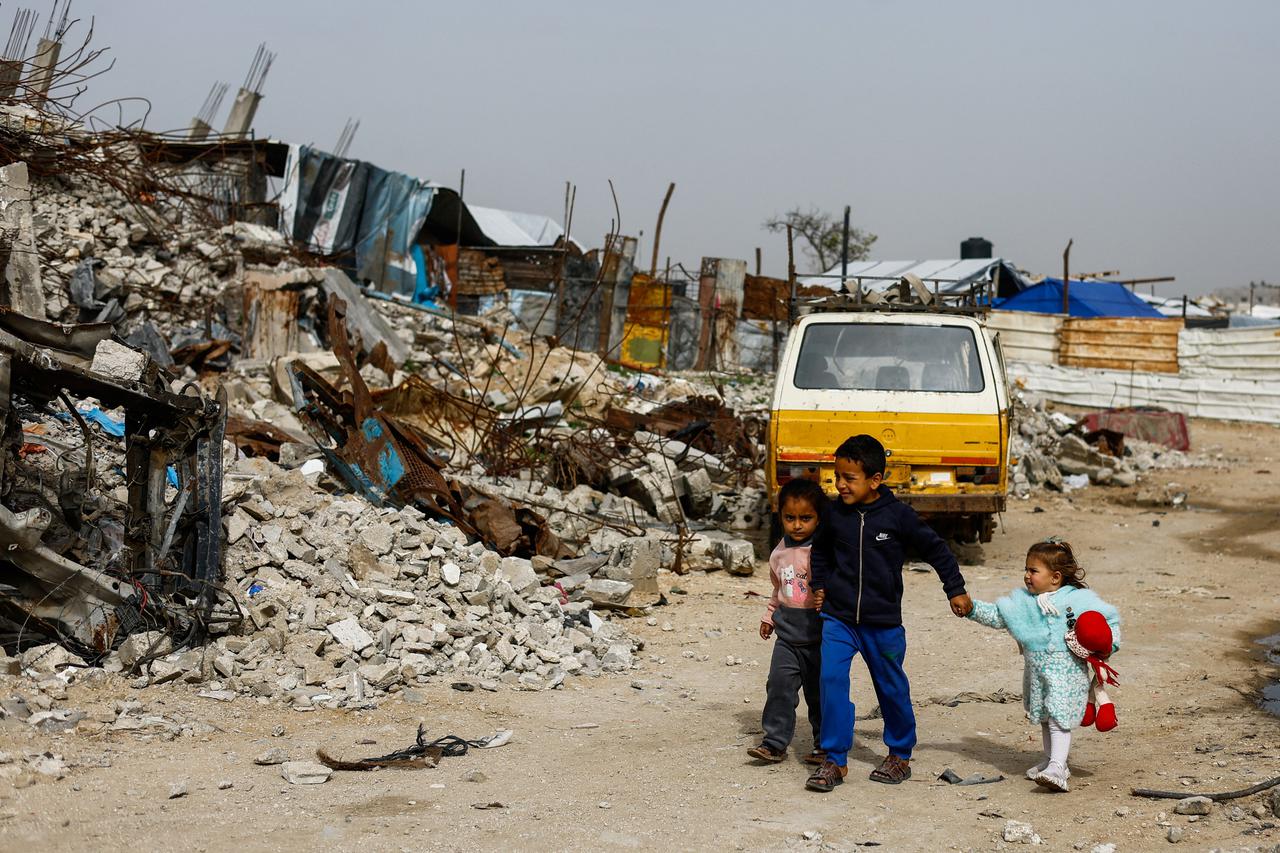 Palestinians walk past the rubble of residential buildings destroyed during the war, in Gaza City