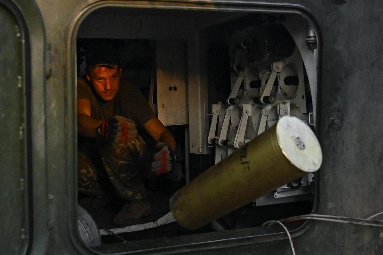 Ukrainian artillerist throughs away a used sell from a self-propelled howitzer during firing towards Russian troops near the town of Chasiv Yar