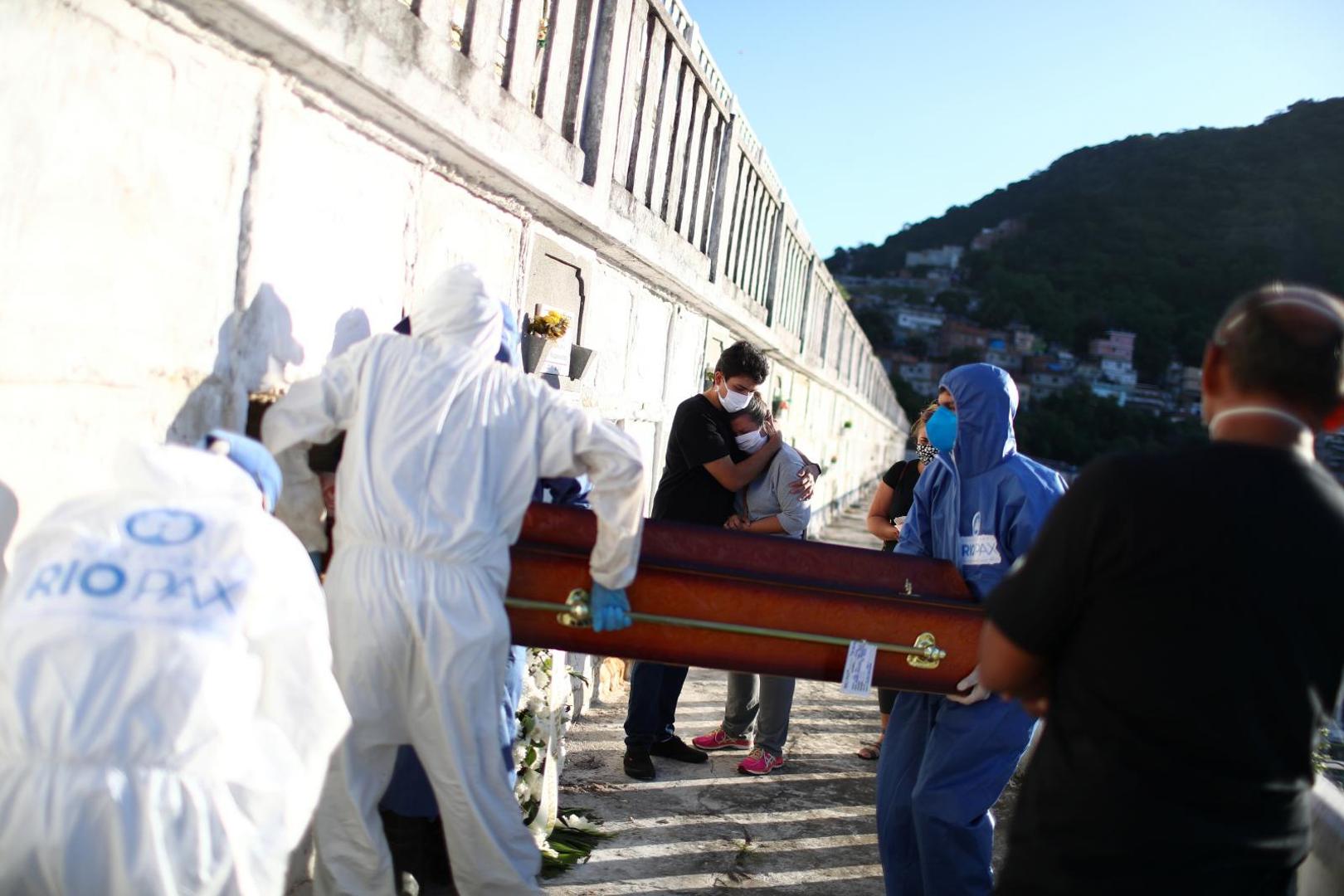 Spread of the coronavirus disease (COVID-19) in Rio de Janeiro Family members of Andre Wendel, who died from the coronavirus disease (COVID-19), embrace as gravediggers wearing protective suits bury his coffin at the Sao Joao Batista cemetery in Rio de Janeiro, Brazil May 28, 2020. REUTERS/Pilar Olivares PILAR OLIVARES