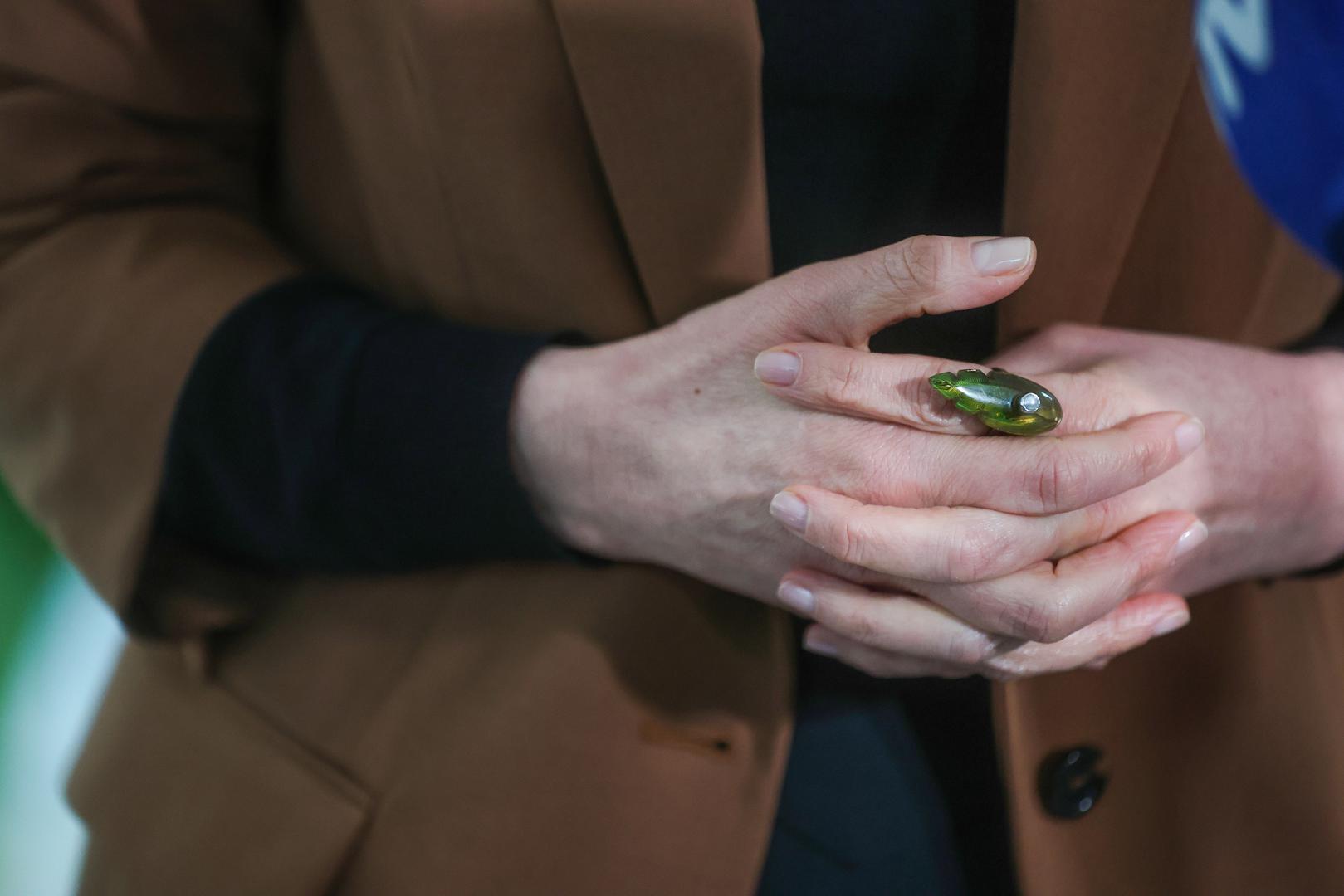 Osim broševa, pozornost je privlačio i upečatljiv prsten na njezinoj ruci. Riječ je o prstenu zelene boje s istaknutim bijelim biserom, koji je poslužio kao savršen "statement" komad i unio dašak boje u neutralnu paletu odjeće.