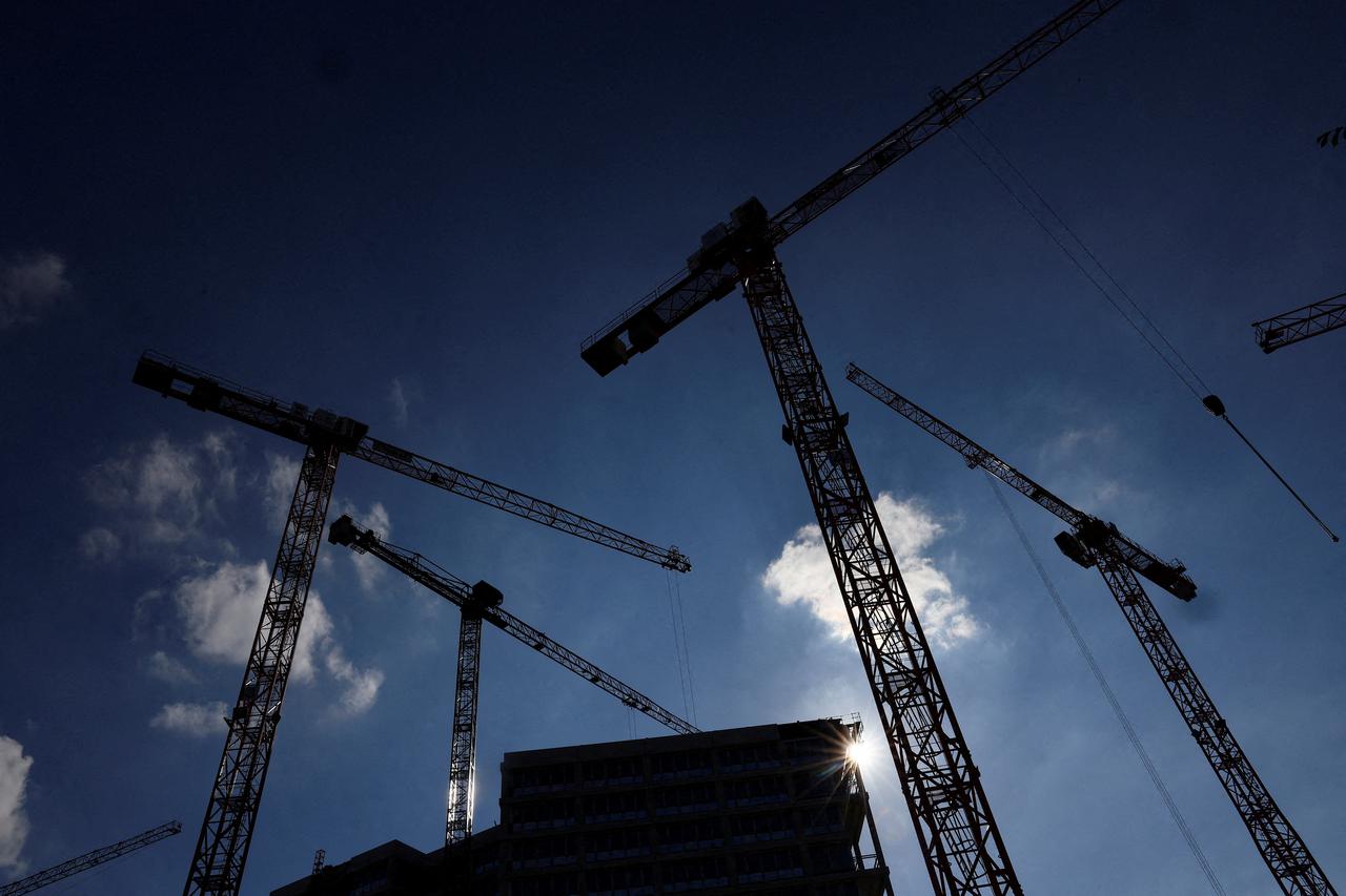 FILE PHOTO: Cranes and a construction site silhouetted against the sun