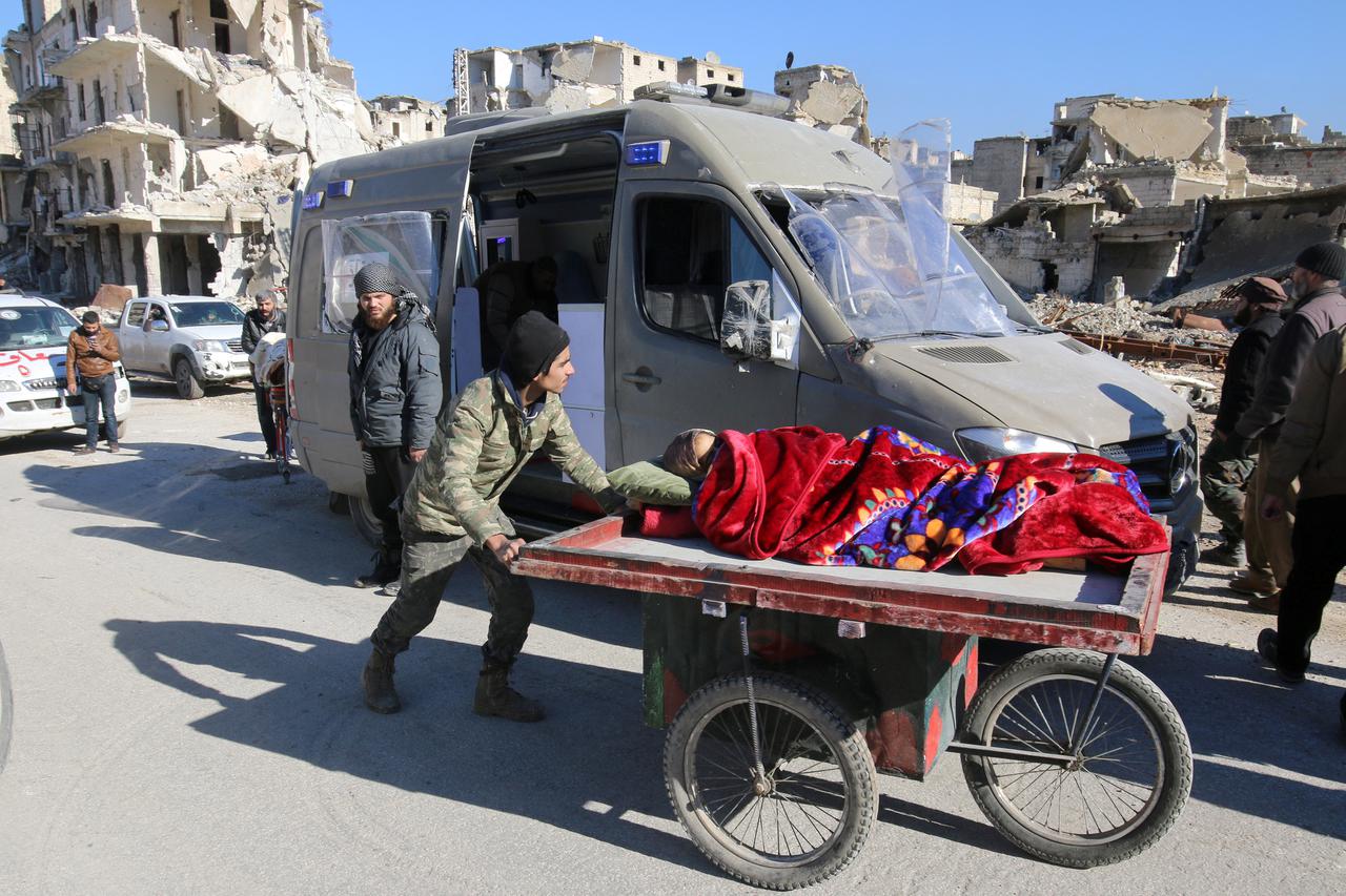 A man pushes a cart with a woman lying on it as vehicles wait to evacuate people from a rebel-held sector of eastern Aleppo, Syria December 15, 2016. REUTERS/Abdalrhman Ismail     TPX IMAGES OF THE DAY
