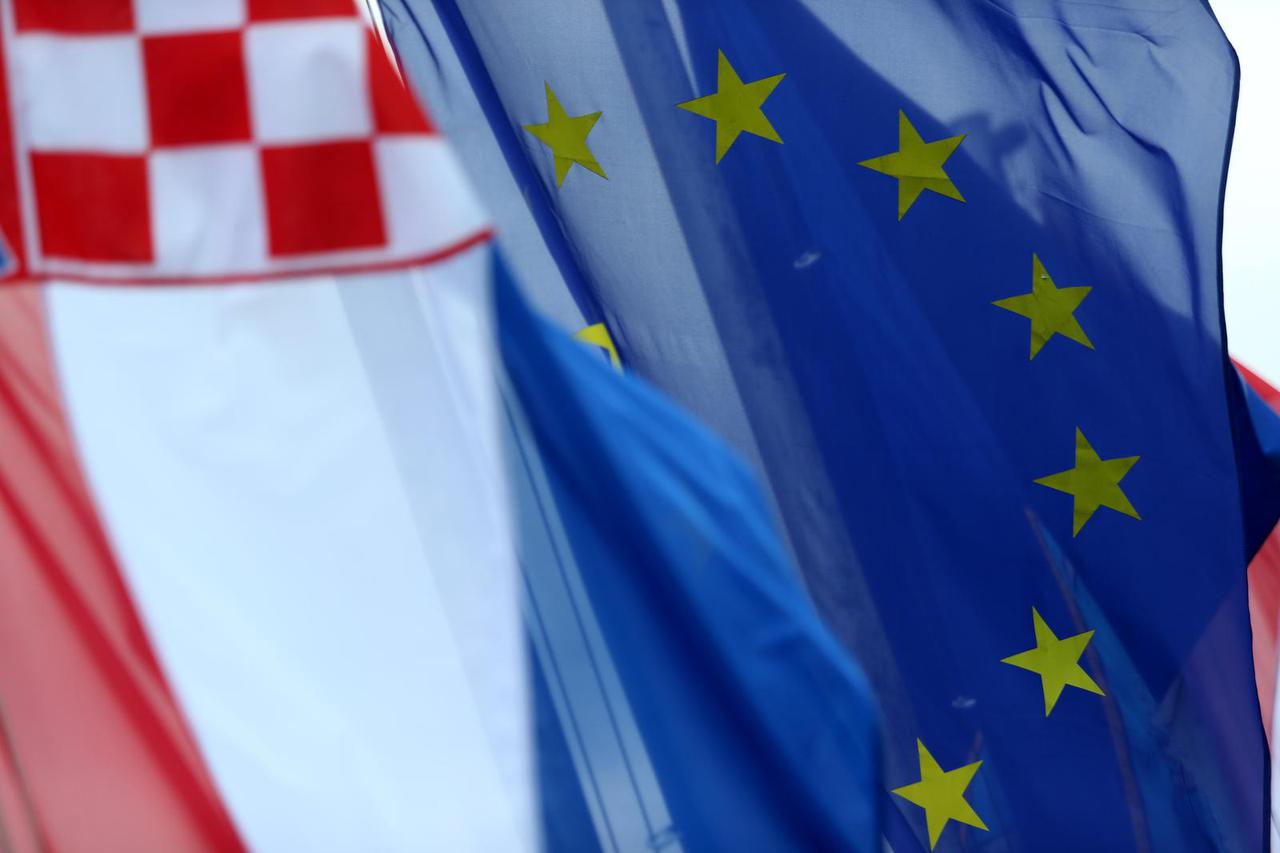 Zastave Hrvatske i Europske unije podignute prema vedrom nebu i suncu