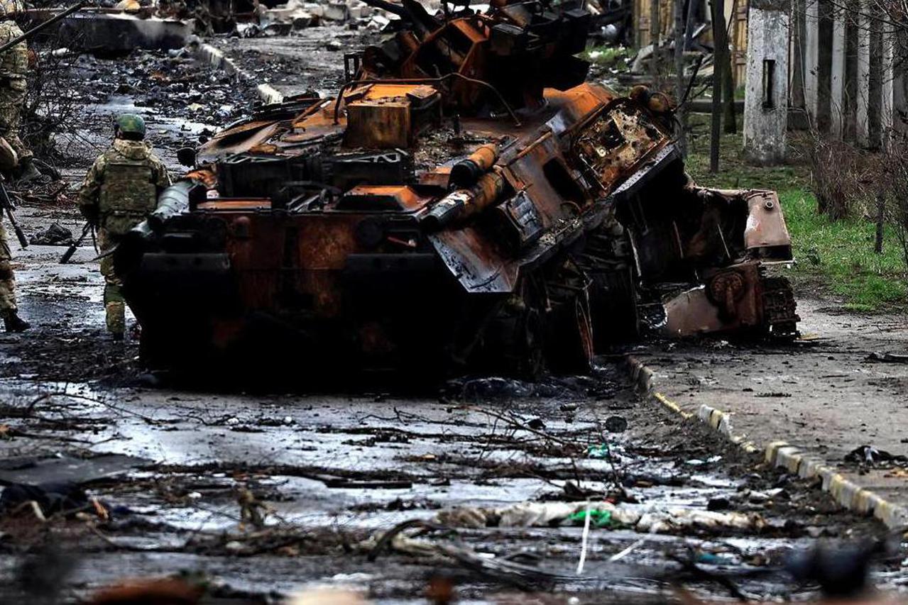FILE PHOTO: A soldier takes a photograph of his comrade as he poses beside a destroyed Russian tank and armoured vehicles, amid Russia's invasion on Ukraine in Bucha, in Kyiv region