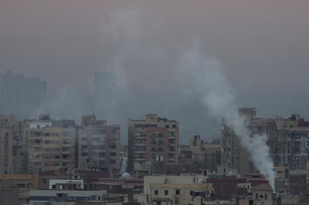 A view of old houses with hotels and the Great Pyramids during sunset with fog from air pollution over the Egypt's capital of Cairo