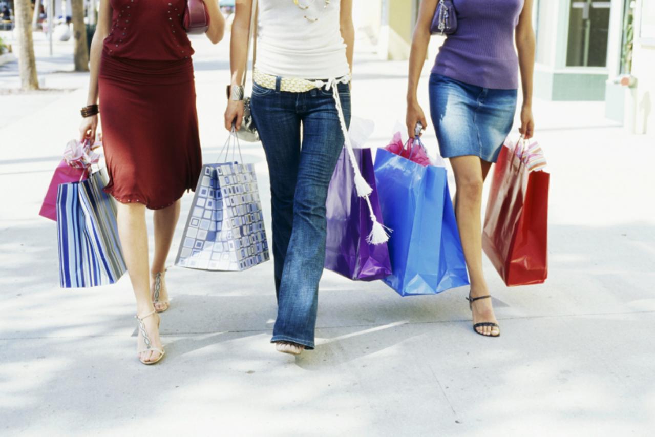 'Low section view of three women walking and holding shopping bags'