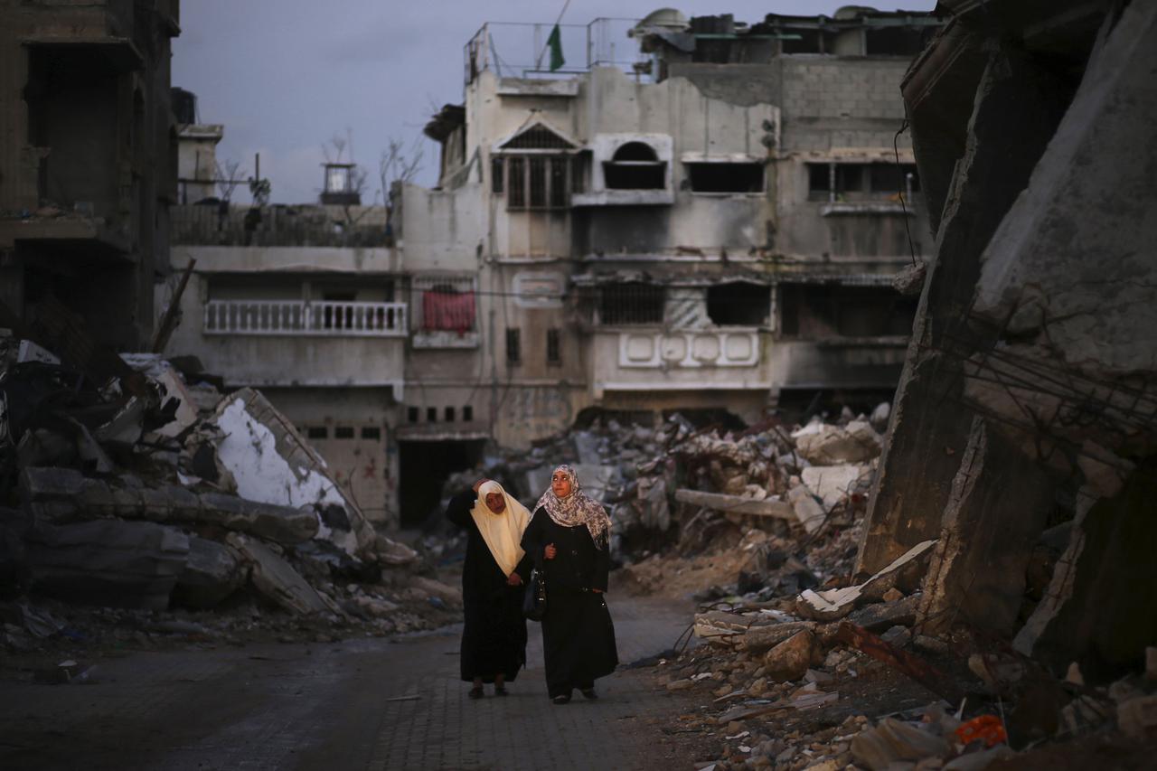 Palestinian women walk near the ruins of houses, which witnesses said were destroyed by Israeli shelling during the most recent conflict between Israel and Hamas, in the east of Gaza City December 1, 2014. According to housing minister Mufeed al-Hasayna, 