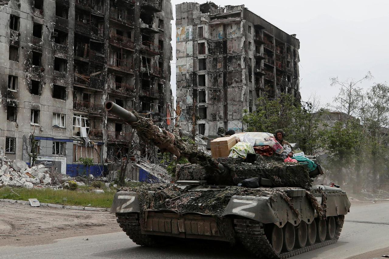 Service members of pro-Russian troops drive a tank along a street in Popasna