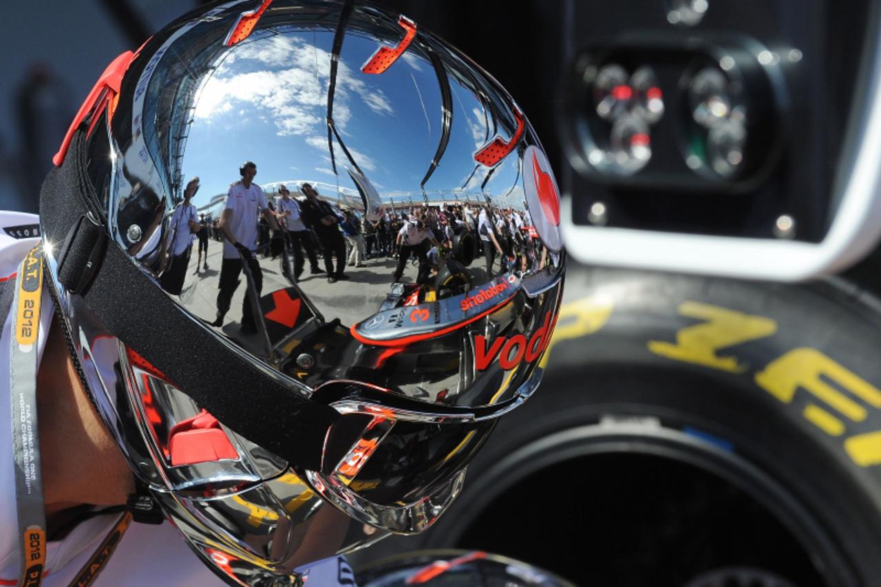 'The McLaren-Mercedes of Jenson Button of Britain is reflected in the helmet of a pit crew member as they practice pit stops ahead of Formula One\'s Australian Grand Prix in Melbourne on March 18, 201