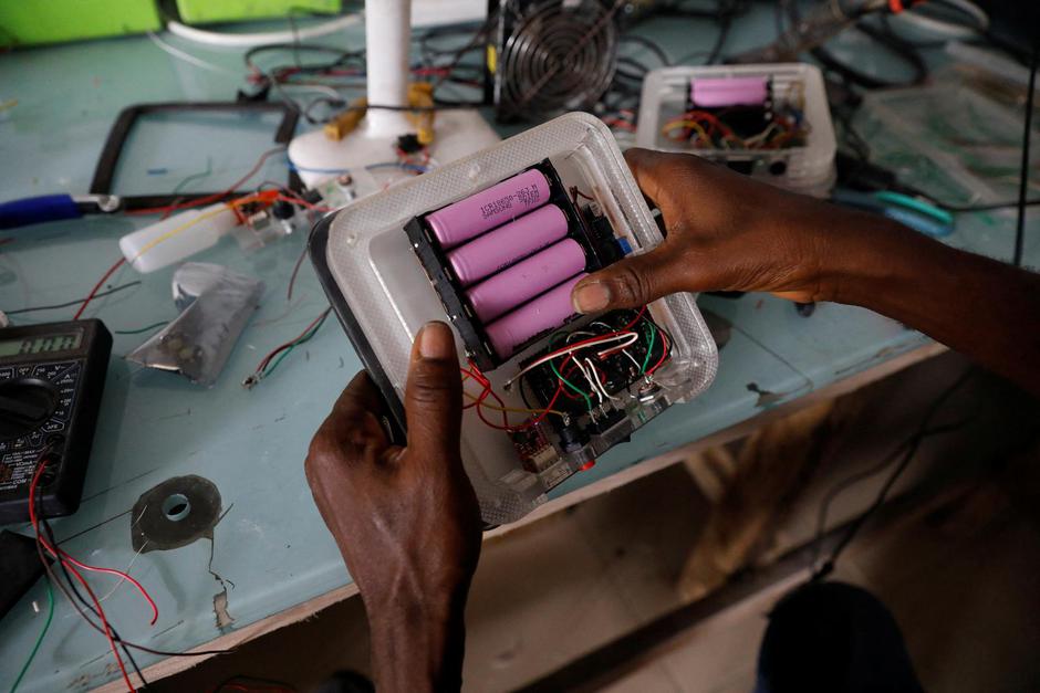 An employee inserts lithium-ion cells from old laptop battery packs into a solar lantern at the Quadloop recycling facility in Lagos