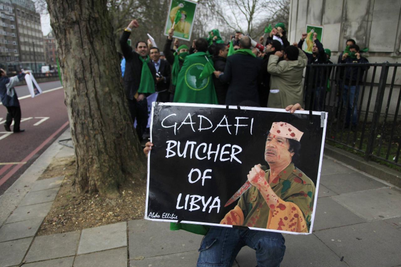 \'An anti-government protester holds a placard in front of supporters of Libyan leader, Muammar Gaddafi, during a demonstration outside the Libyan embassy in London February 17, 2011. REUTERS/Stefan W