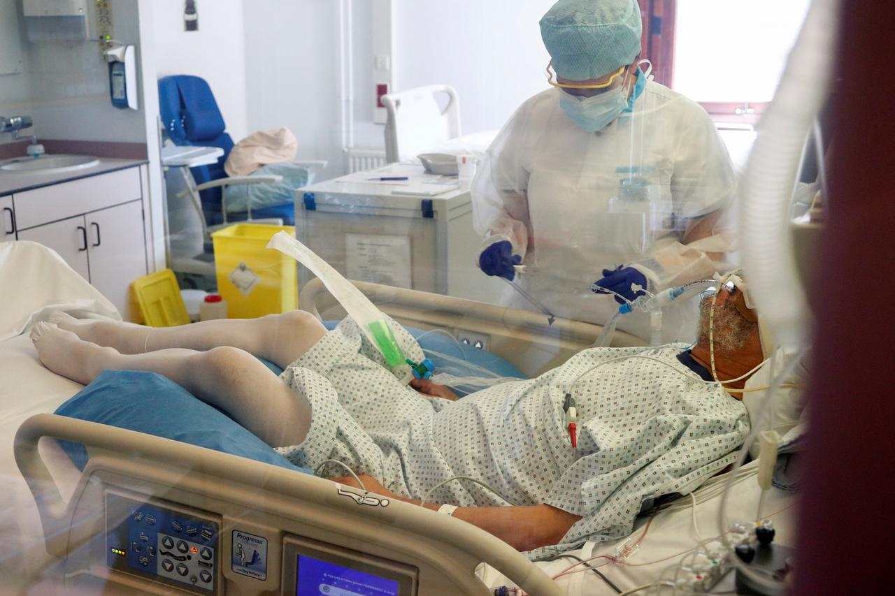 A nurse wearing a protective suit and a face mask treats a patient suffering from the coronavirus disease (COVID-19) in a hospital in Brussels