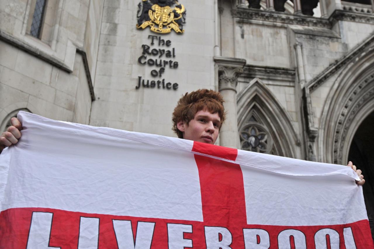 'A fan of Liverpool football club poses for pictures outside the High Court in London, on October 12, 2010. The legal battle for control of Liverpool was set to start at London\'s High Court Tuesday w