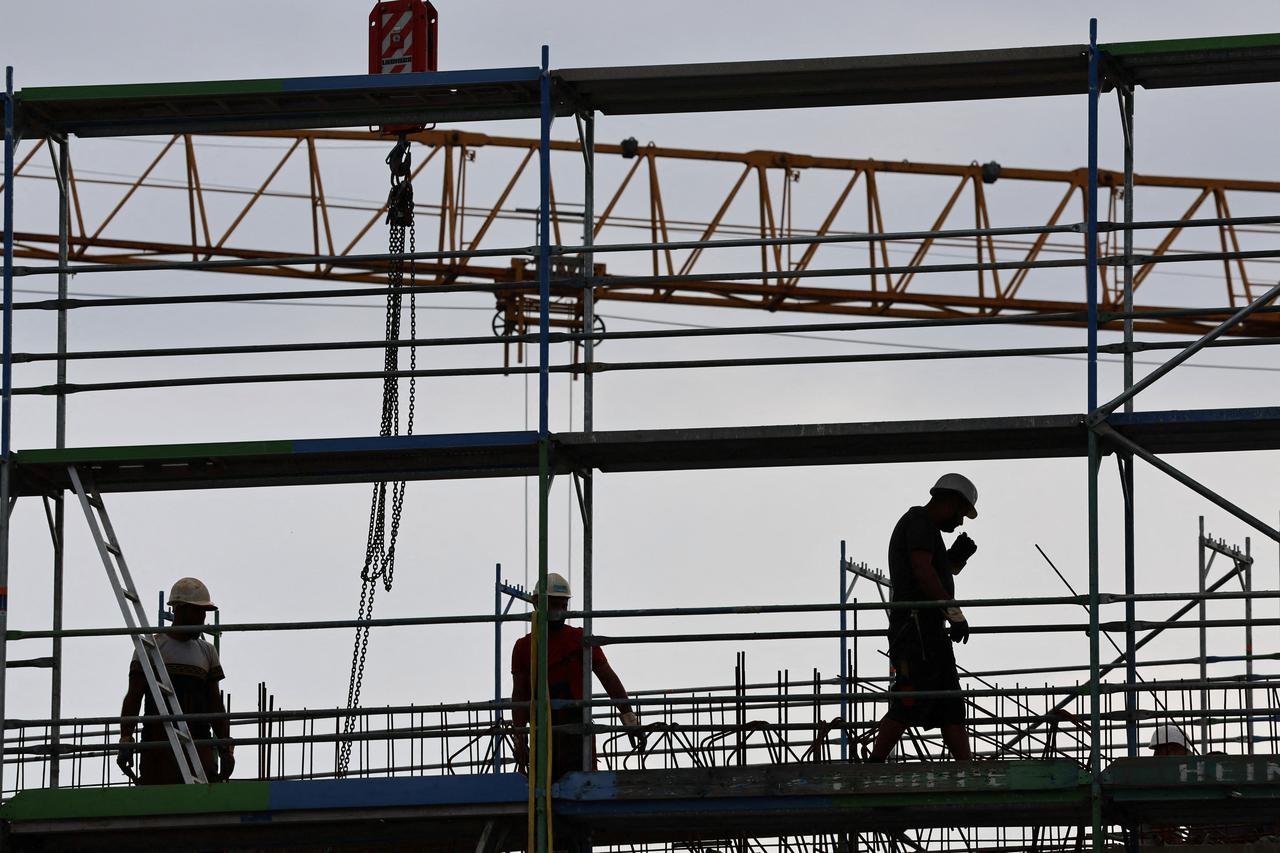 FILE PHOTO: Builders work on scaffoldings at the construction site for a shopping mall in Monheim
