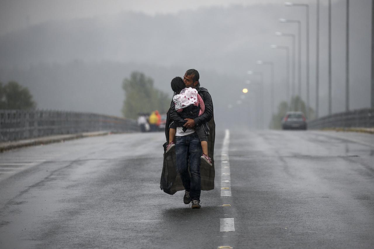 Syrian refugee kisses his daughter as he walks through a rainstorm towards Greece's border with Macedonia, near the Greek village of Idomeni, September 10, 2015. Reuters and The New York Times shared the Pulitzer Prize for breaking news photography for im