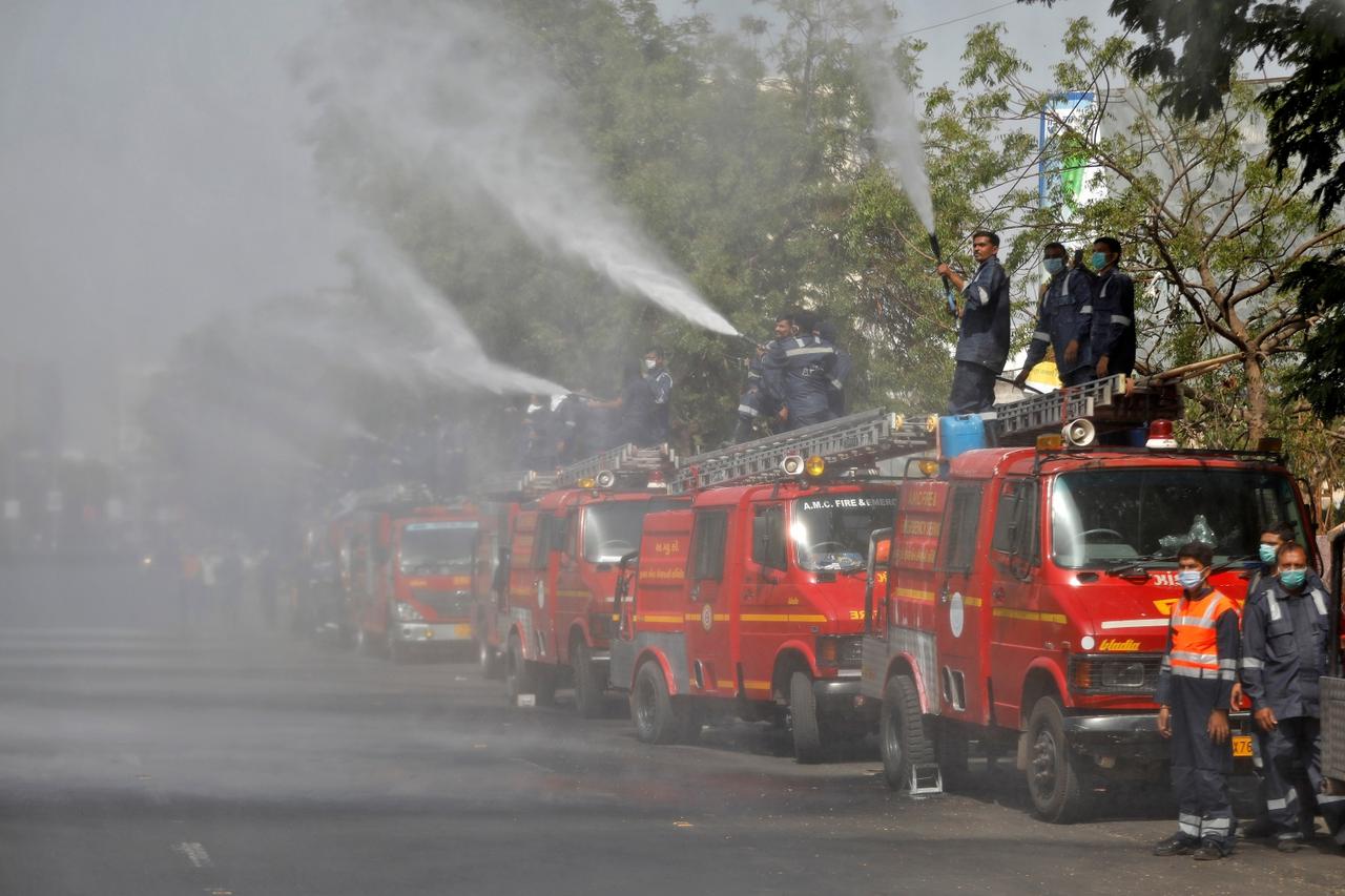Members of Fire and Emergency Services decontaminate a road in Ahmedabad