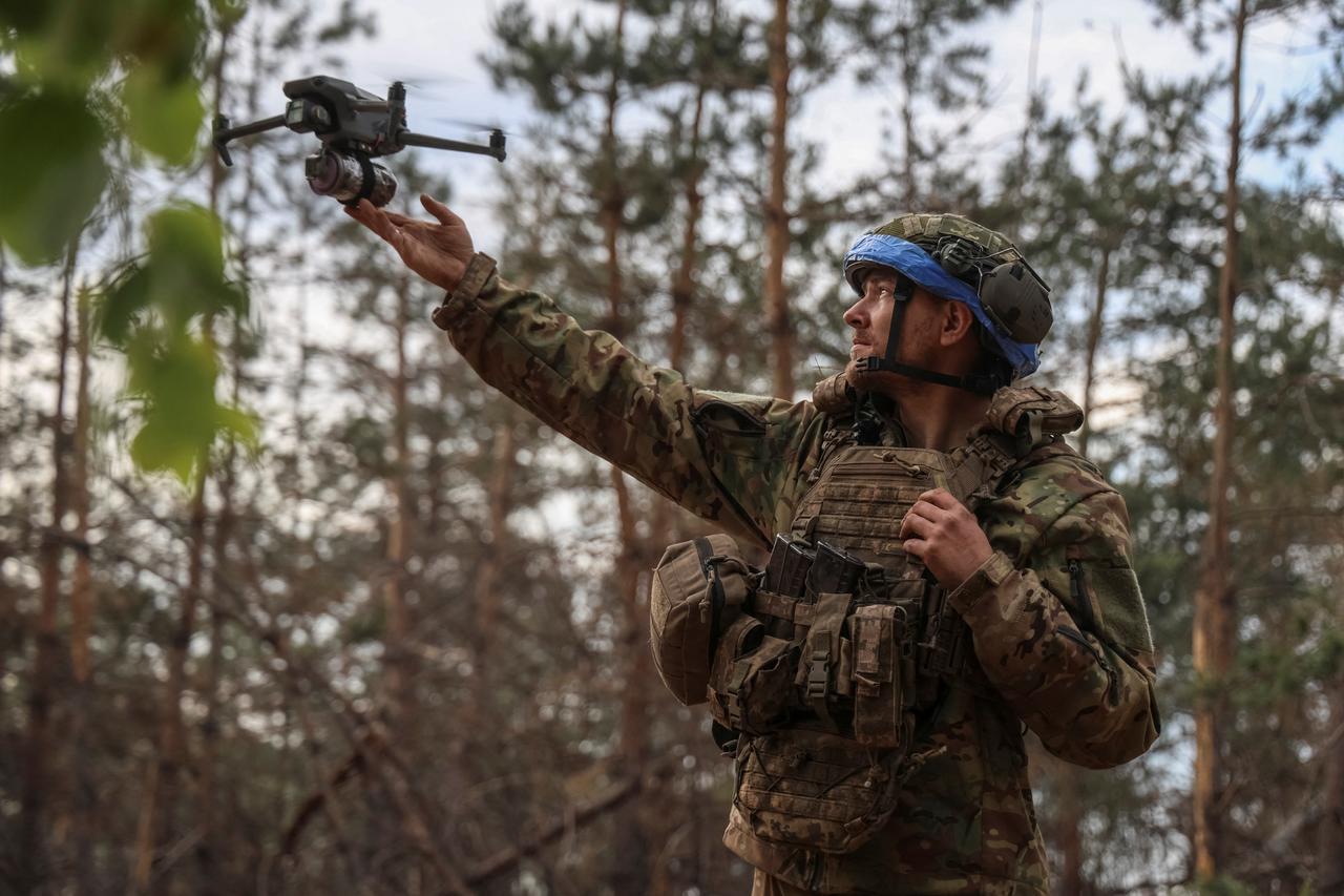 A Ukrainian serviceman launches a drone, with a grenade attached to it, to fly it over the positions of Russian troops at a frontline in the Donbas region